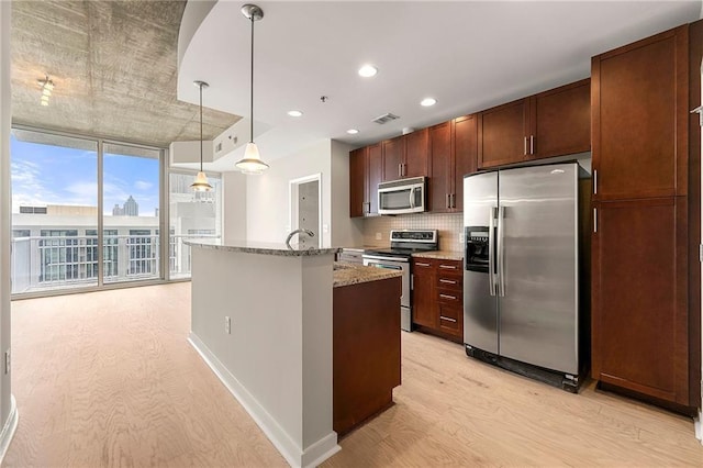 855 Peachtree St NE Unit 3205, Atlanta, GA 30308 - kitchen with appliances with stainless steel finishes, light wood-style flooring, tasteful backsplash, light stone countertops, and a center island with sink