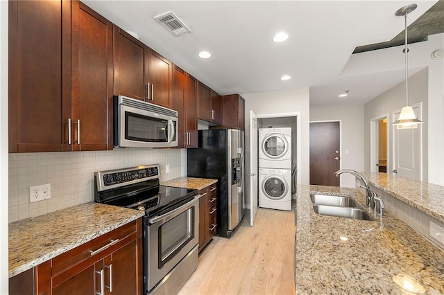 855 Peachtree St NE Unit 3205, Atlanta, GA 30308 - kitchen with stainless steel appliances, stacked washing machine and dryer, a sink, light wood-type flooring, and tasteful backsplash
