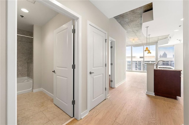 855 Peachtree St NE Unit 3205, Atlanta, GA 30308 - corridor with a sink, baseboards, light wood-style flooring, and a wall of windows