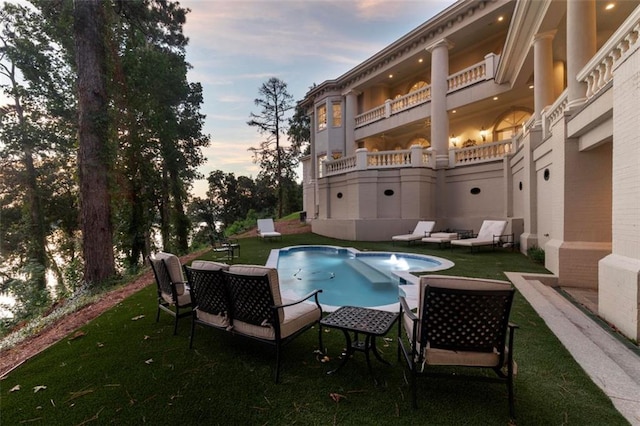 pool at dusk featuring a lawn