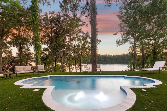 pool at dusk featuring a yard and a water view