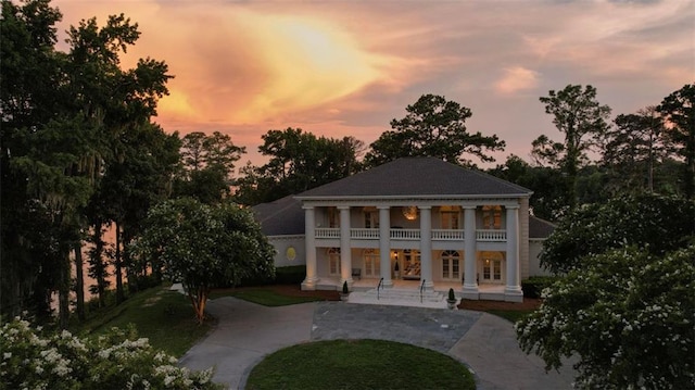 back house at dusk featuring a patio and a yard