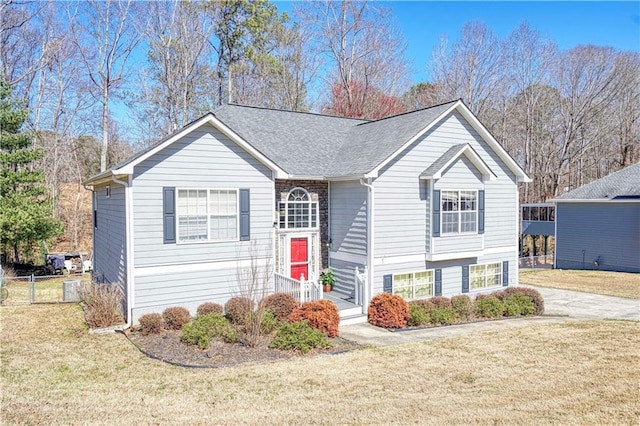 view of front of property with roof with shingles, a front lawn, and fence