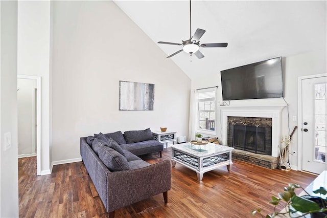 living room featuring high vaulted ceiling, wood finished floors, a stone fireplace, baseboards, and ceiling fan