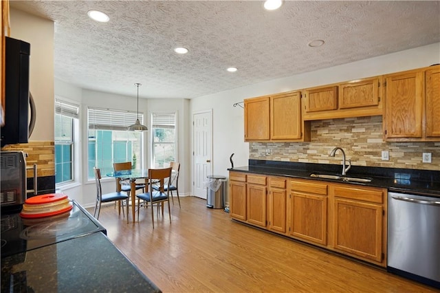 kitchen featuring backsplash, light wood-style flooring, brown cabinets, stainless steel dishwasher, and a sink