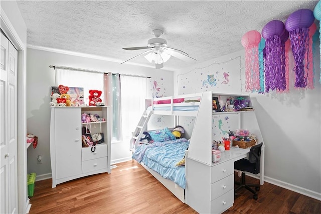 bedroom with a closet, a textured ceiling, wood finished floors, and a ceiling fan