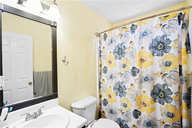 bathroom with a shower with shower curtain, toilet, vanity, and a textured ceiling