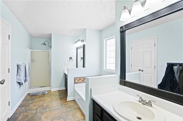 bathroom with a stall shower, a textured ceiling, baseboards, a bath, and vanity