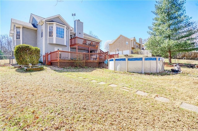 exterior space featuring fence, a fenced in pool, a chimney, a deck, and a lawn