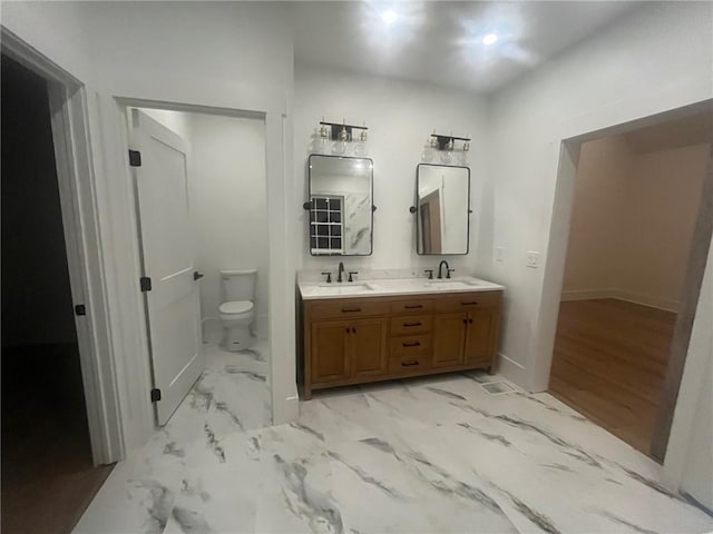 full bath with marble finish floor, a sink, toilet, and double vanity