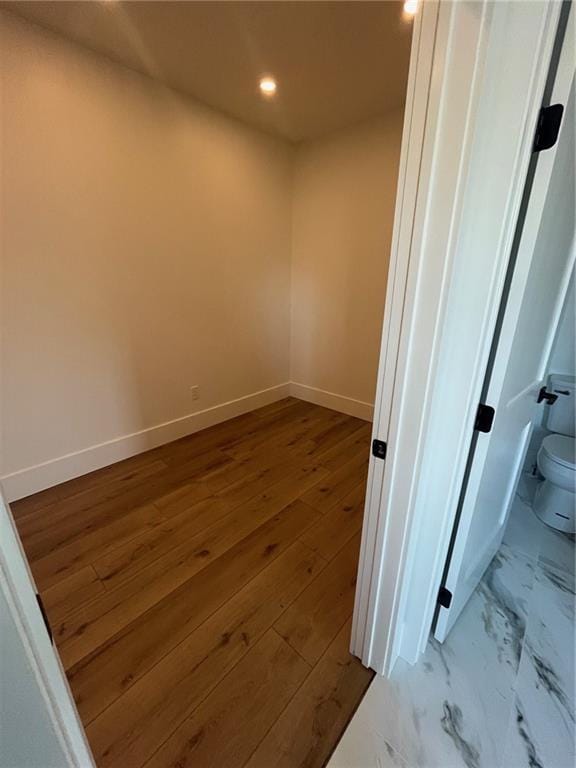 empty room featuring recessed lighting, wood finished floors, and baseboards