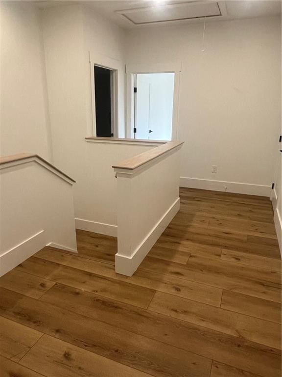 corridor with attic access, an upstairs landing, and wood finished floors