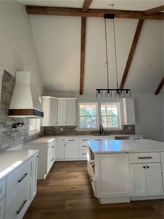 kitchen featuring pendant lighting, a sink, white cabinetry, light countertops, and custom range hood