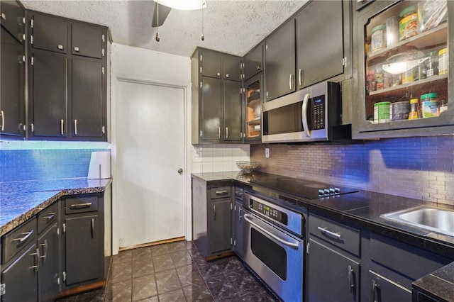 kitchen with ceiling fan, dark tile patterned floors, tasteful backsplash, a textured ceiling, and stainless steel appliances