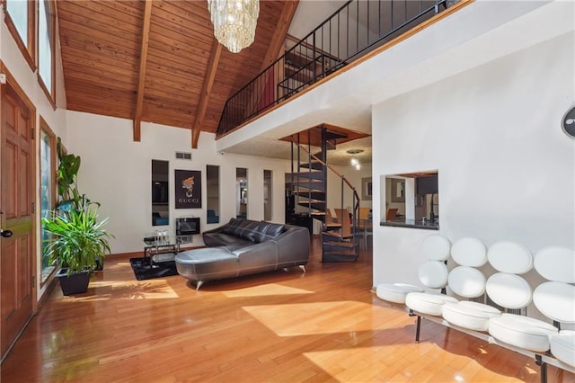 living room with high vaulted ceiling, a notable chandelier, beamed ceiling, and hardwood / wood-style flooring