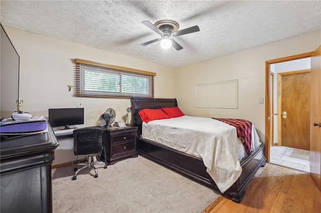 bedroom with ceiling fan, a textured ceiling, and light hardwood / wood-style floors