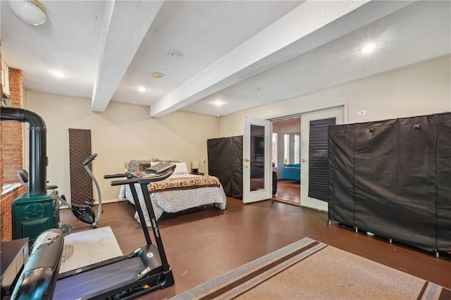 exercise area with a textured ceiling, a wood stove, and french doors