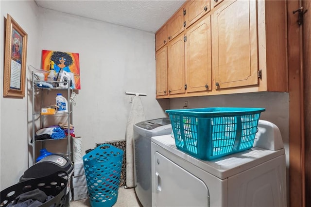 laundry area with cabinets, a textured ceiling, and washer and dryer