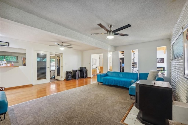 interior space with a textured ceiling, ceiling fan, and light hardwood / wood-style flooring