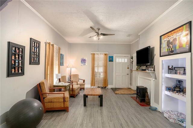 sitting room featuring ceiling fan, a textured ceiling, light hardwood / wood-style flooring, and crown molding