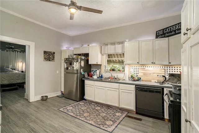 kitchen with sink, wood-type flooring, black dishwasher, and stainless steel refrigerator