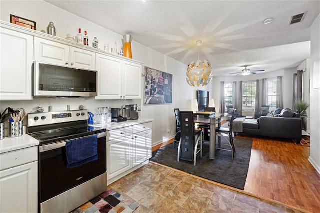 kitchen with wood-type flooring, decorative light fixtures, white cabinets, ceiling fan with notable chandelier, and appliances with stainless steel finishes