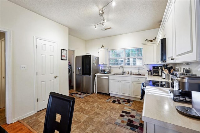 kitchen featuring white cabinets, a textured ceiling, and appliances with stainless steel finishes