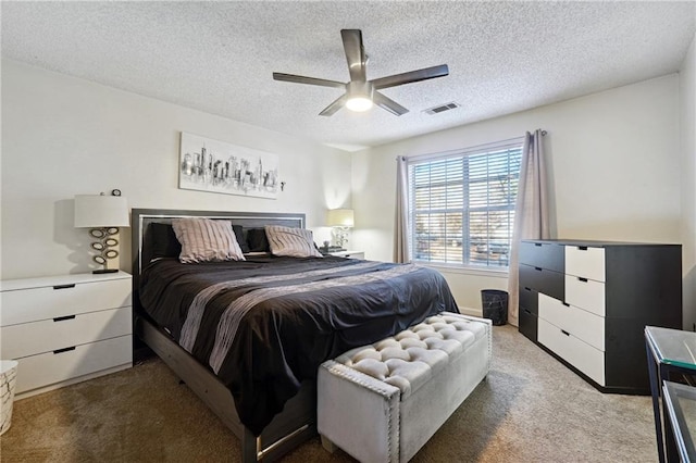 bedroom with ceiling fan, carpet floors, and a textured ceiling