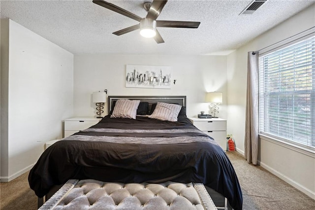 carpeted bedroom with ceiling fan and a textured ceiling