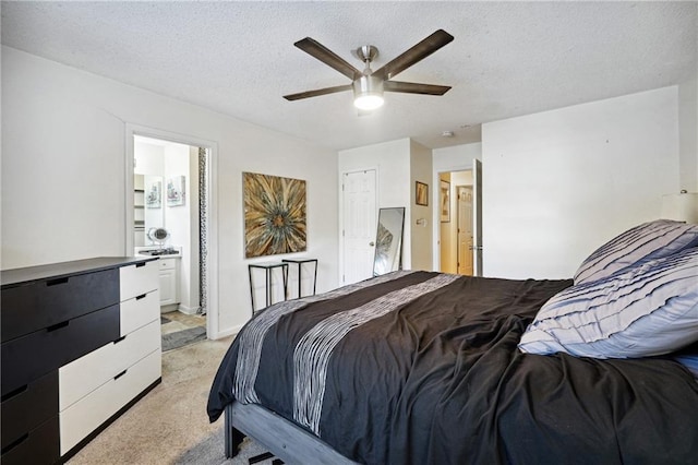 carpeted bedroom featuring a textured ceiling, ensuite bathroom, and ceiling fan