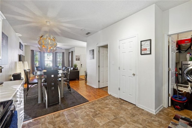 dining space featuring a chandelier, a textured ceiling, and light wood-type flooring