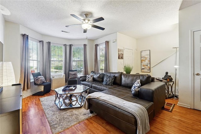 living room with ceiling fan, wood-type flooring, and a textured ceiling