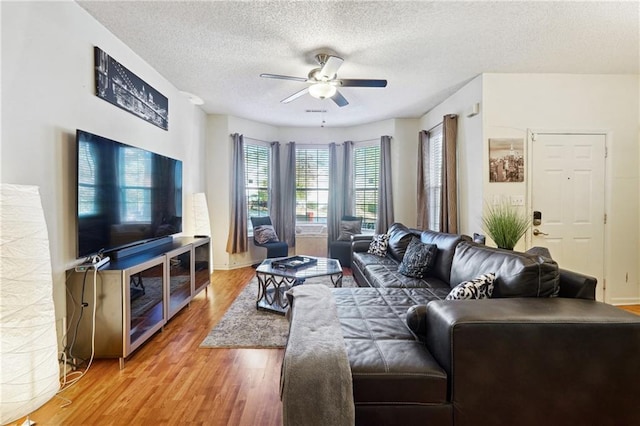 living room featuring hardwood / wood-style floors, ceiling fan, and a textured ceiling