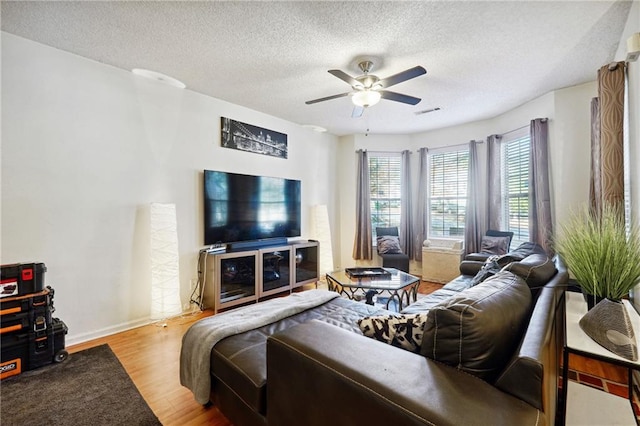 living room with ceiling fan, a textured ceiling, and light hardwood / wood-style flooring