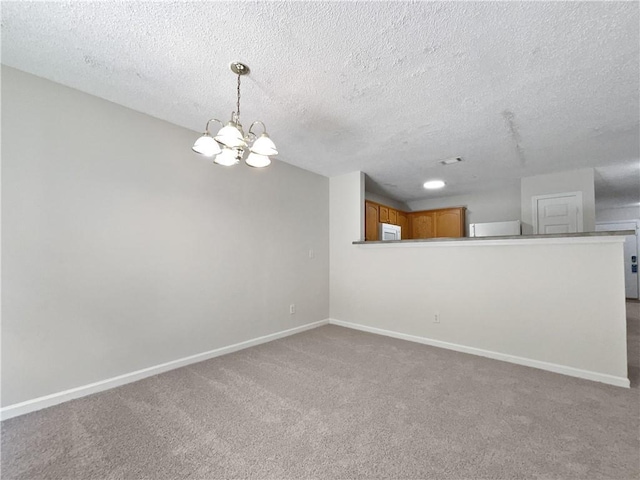 carpeted empty room with a textured ceiling and a notable chandelier