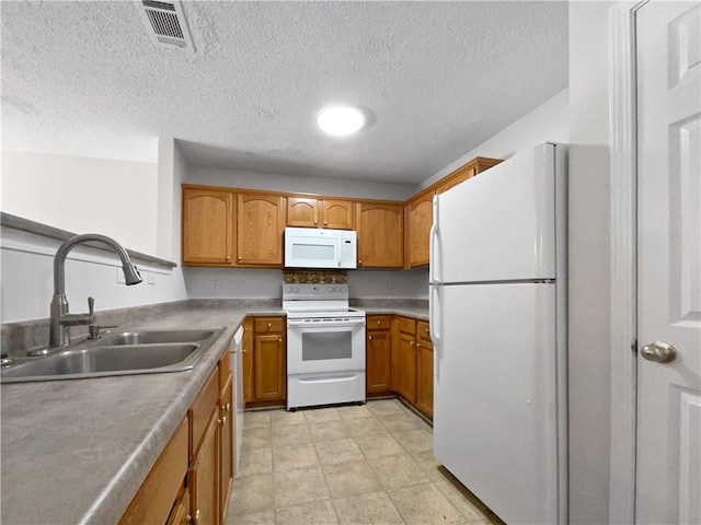 kitchen with a textured ceiling, white appliances, and sink