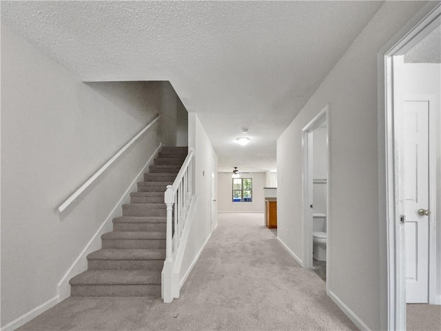 stairs featuring carpet floors and a textured ceiling