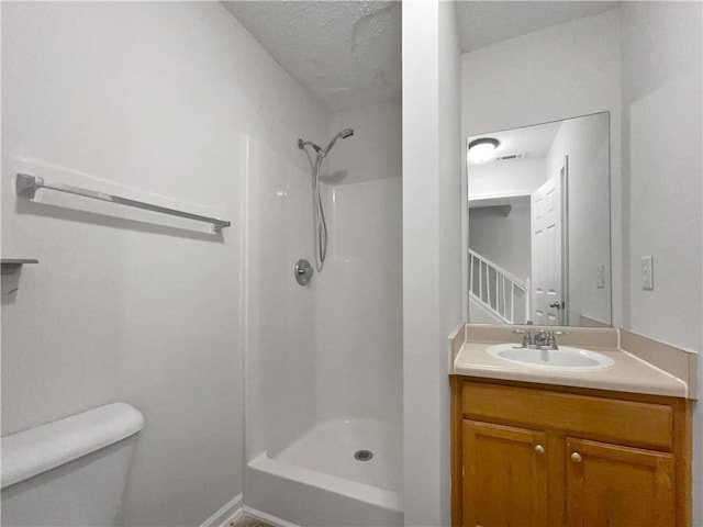 bathroom with a textured ceiling, vanity, toilet, and walk in shower