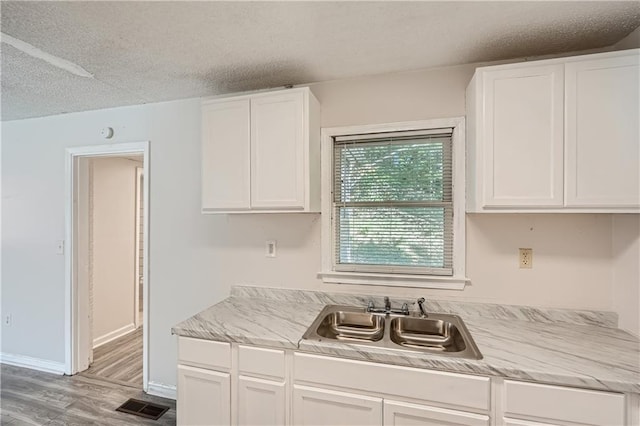 kitchen with white cabinetry, sink, a textured ceiling, and hardwood / wood-style flooring