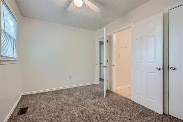 unfurnished bedroom featuring ceiling fan, light carpet, and a textured ceiling