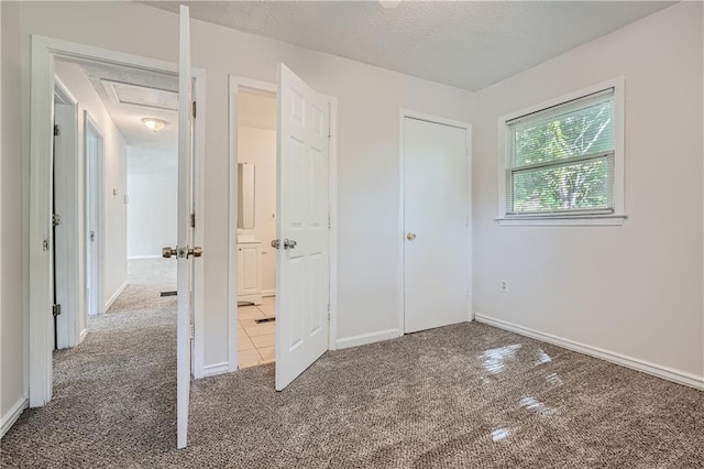 unfurnished bedroom with carpet flooring, a textured ceiling, and a closet