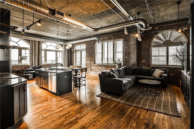 living room with visible vents, light wood-style floors, brick wall, and rail lighting