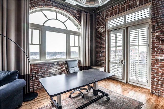 office space featuring wood finished floors and brick wall