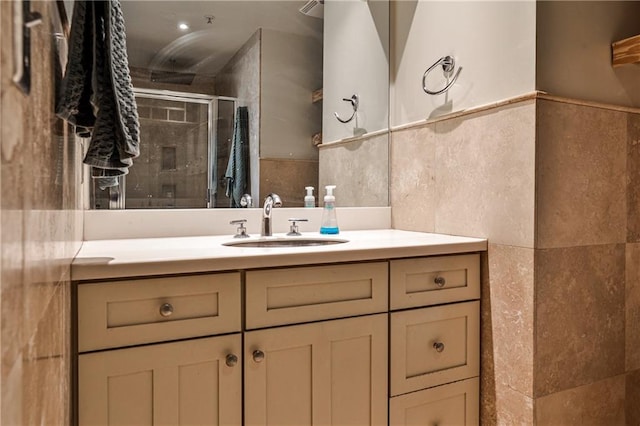 full bathroom featuring a shower stall, vanity, and tile walls