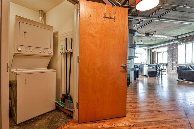 washroom with laundry area, wood finished floors, and stacked washing maching and dryer