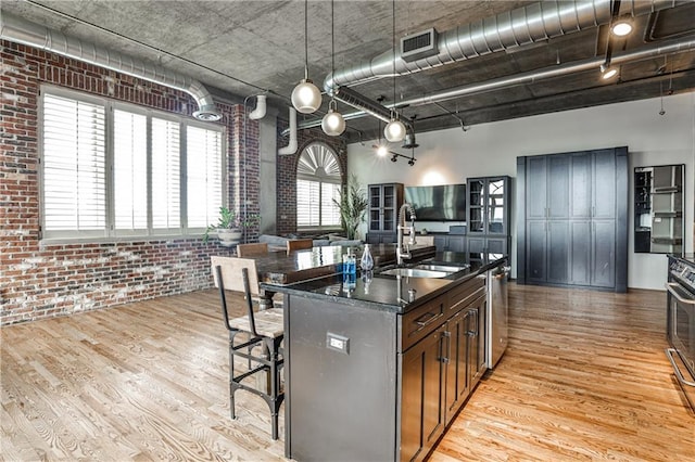 kitchen featuring dark countertops, visible vents, light wood-style flooring, and brick wall