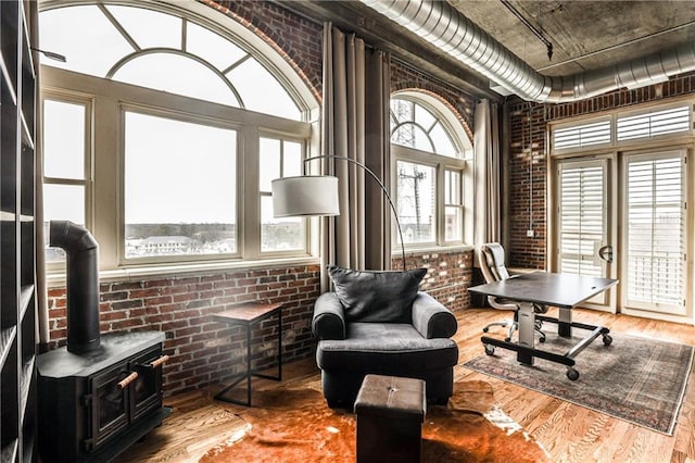 office space with a wealth of natural light, wood finished floors, and brick wall