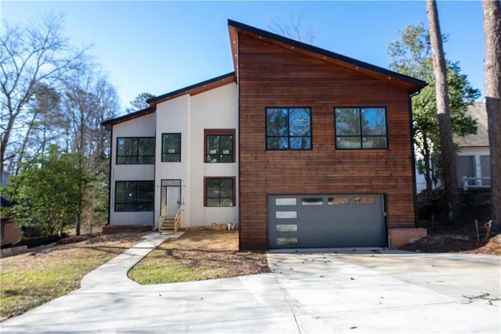 4238 Paces Ferry Rd SE, Atlanta, GA 30339 - modern home featuring entry steps, concrete driveway, an attached garage, and stucco siding