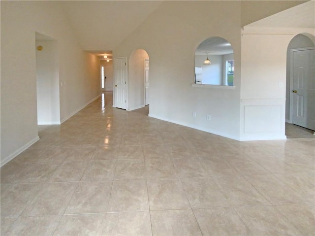 empty room with arched walkways and light tile patterned flooring