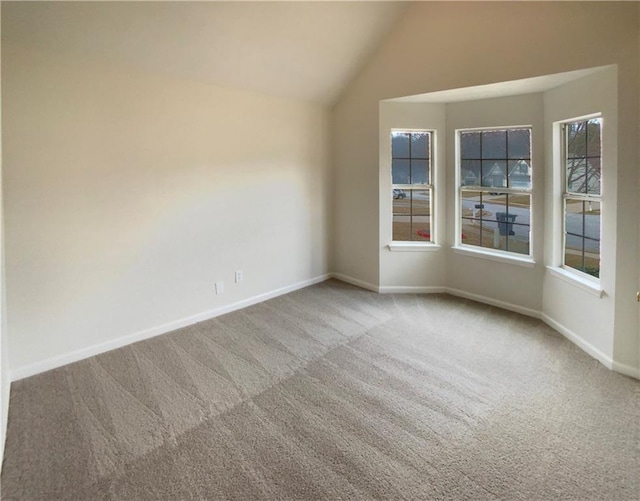 carpeted empty room with lofted ceiling and baseboards